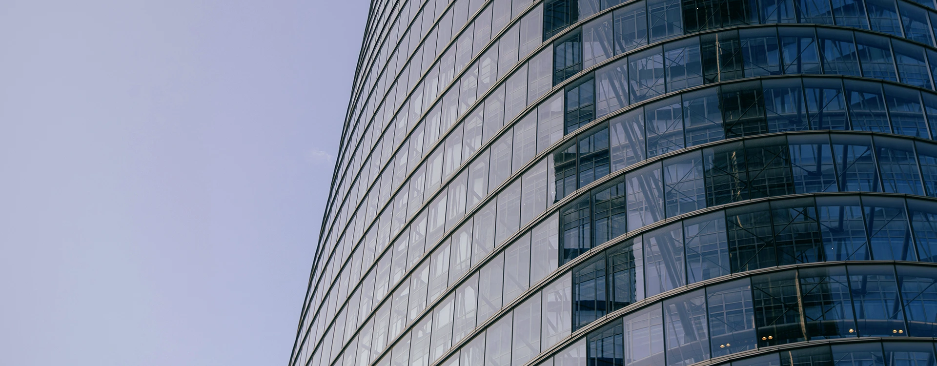 A Rounded Glass Office Building At Dusk.